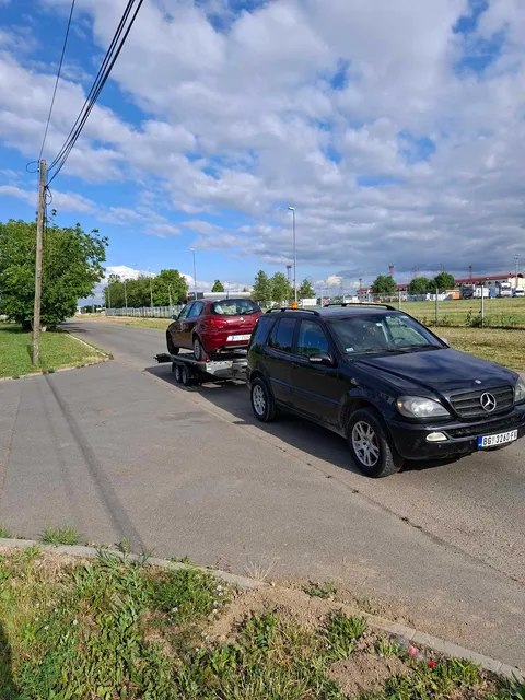 Vučno vozilo transportuje automobil na putu